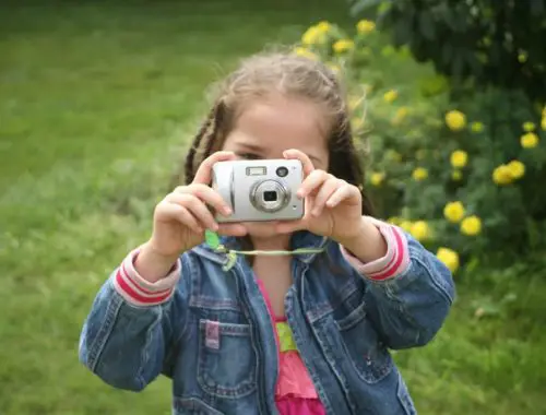 A little girl taking a picture with a digital camera